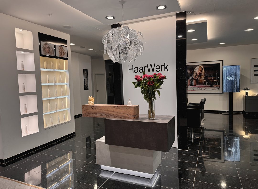 Empfang mit HaarWerk-Schriftzug, Blumenstrauß und Hängeleuchte im HaarWerk Oberpollinger