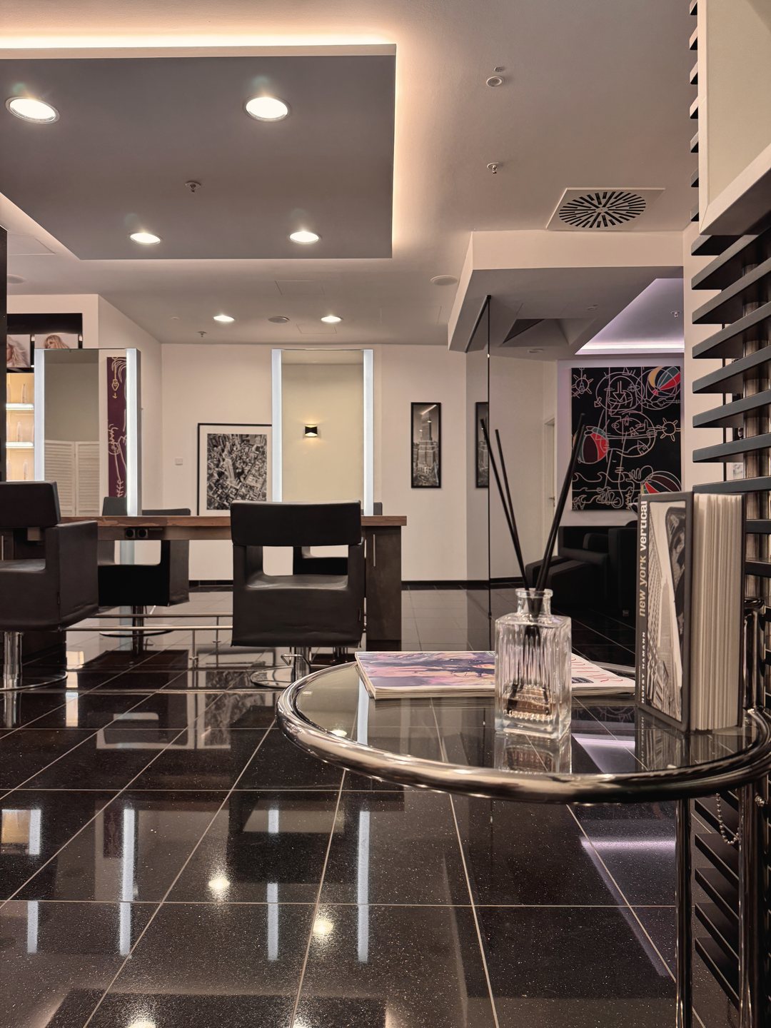 Blick in den Salon mit Glastisch, Friseurstühlen und Spiegeln